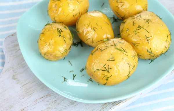 Boiled potatoes on platen on wooden board on napkin — Stock Photo, Image