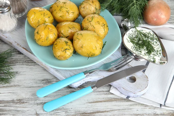 Kokt potatis på valsen på träplatta nära servett på träbord — Stockfoto