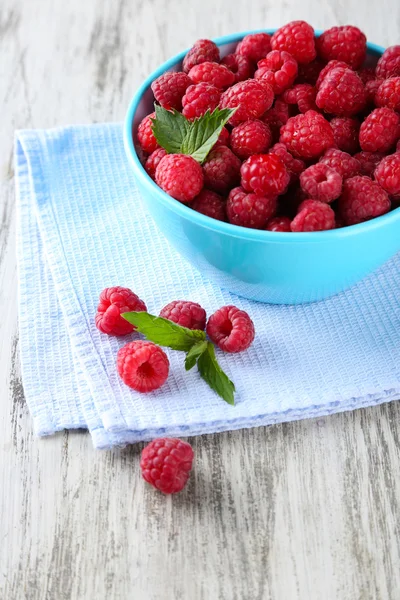 Ripe sweet raspberries in bowl on wooden background — Stock Photo, Image