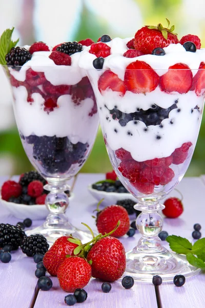 Natural yogurt with fresh berries on wooden table on green background — Stock Photo, Image