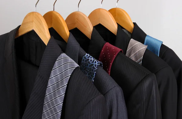 Kostymer och slipsar på galgar på grå bakgrund — Stockfoto