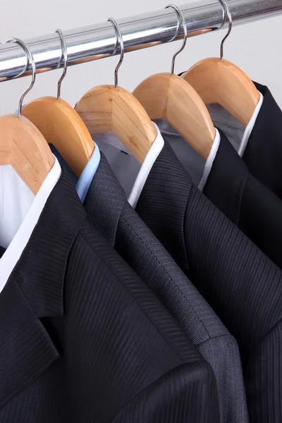 Suits with shirts on hangers on light background — Stock Photo, Image