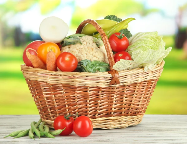 Frisches Gemüse im Korb auf Holztisch vor natürlichem Hintergrund — Stockfoto