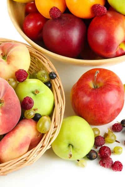 Auswahl an saftigen Früchten in Weidenkorb und Holzschale, isoliert auf weiß — Stockfoto