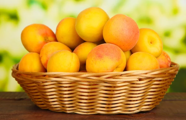 Verse natuurlijke abrikoos in rieten mand op houten tafel — Stockfoto