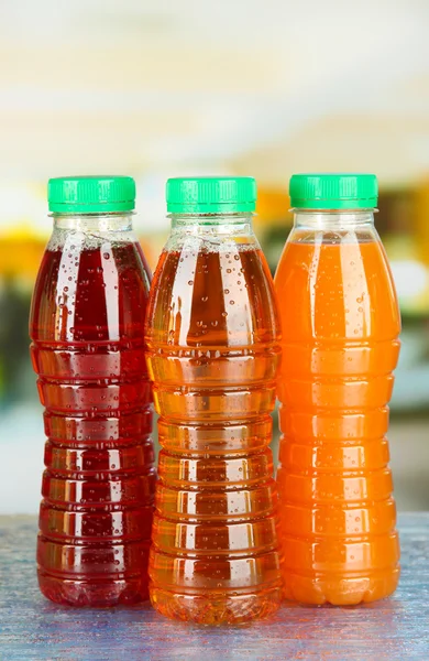 Assortment of bottles with tasty fruit juices on bright background — Stock Photo, Image