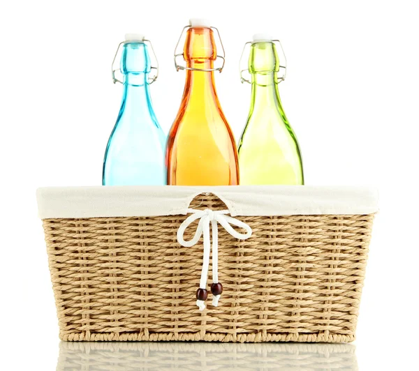Χρώμα γυάλινα μπουκάλια σε ψάθινο καλάθι, απομονωμένα σε λευκό — Φωτογραφία Αρχείου