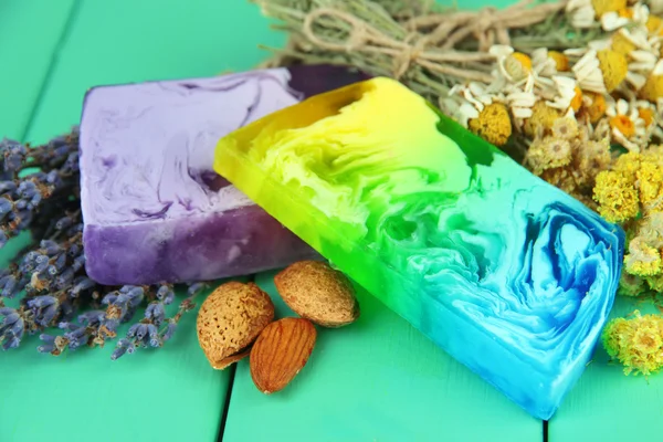 Кусочки мыла ручной работы с травами, на цветном деревянном фоне — стоковое фото