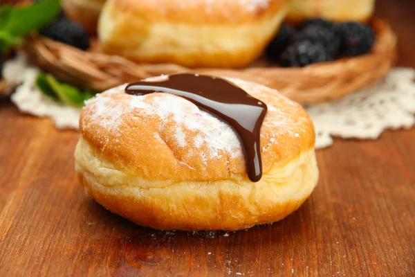 Leckere Donuts mit Schokolade auf Holztisch — Stockfoto