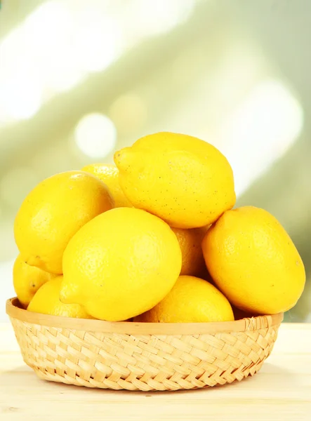 Ripe lemons in wicker basket on table on bright background — Stock Photo, Image