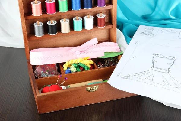 Sewing kit in wooden box,cloth and sketch on wooden table — Stock Photo, Image