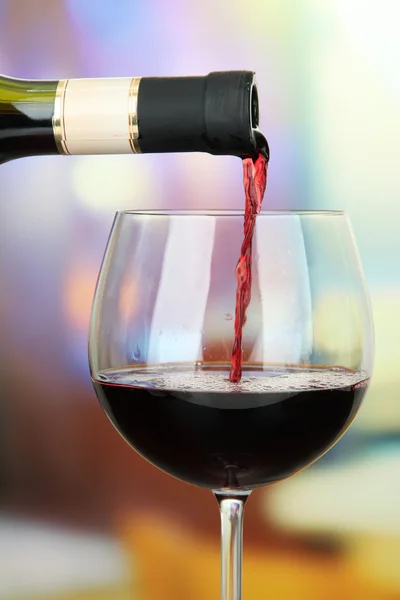 Vino rosso versato in bicchiere di vino, su sfondo luminoso — Foto Stock