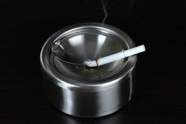 Metal kül tablası ile sigara, siyah üzerine izole — Stok fotoğraf