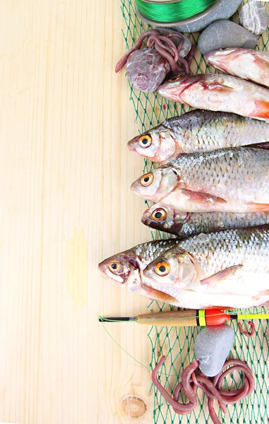 Fishes on fishing net on wooden background — Stock Photo, Image