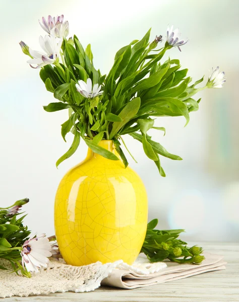 Buquê de belas flores de verão em vaso de cor, na mesa de madeira, no fundo brilhante — Fotografia de Stock