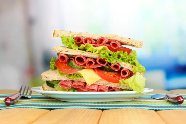 Huge sandwich on wooden table, on bright background — Stock Photo, Image