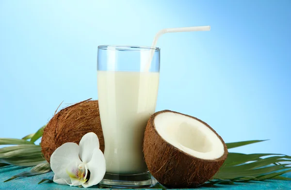 Noci di cocco con vetro di latte, su sfondo blu — Foto Stock