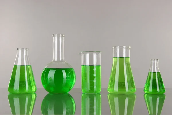 Тестовые трубки с зеленой жидкостью на сером фоне — стоковое фото