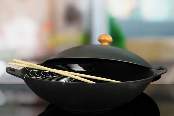 Black wok pan on kitchen oven, close up — Stock Photo, Image