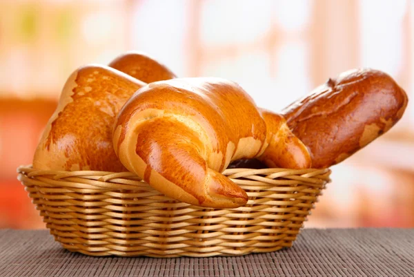 Baked bread in wicker basket on window background — Stock Photo, Image