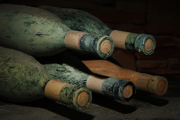 Viejas botellas de vino en bodega vieja, sobre fondo oscuro — Foto de Stock