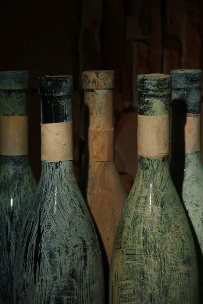 Viejas botellas de vino en bodega vieja, sobre fondo oscuro —  Fotos de Stock