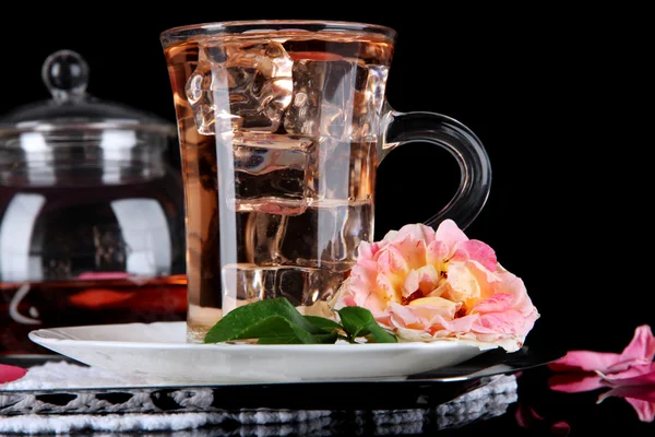Kettle glass cup of ice tea from tea rose on metallic tray on napkin on black background — Stock Photo, Image