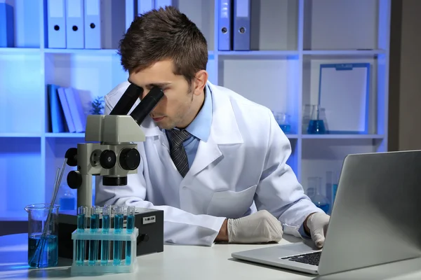 Científico de laboratorio joven mirando el microscopio en el laboratorio —  Fotos de Stock