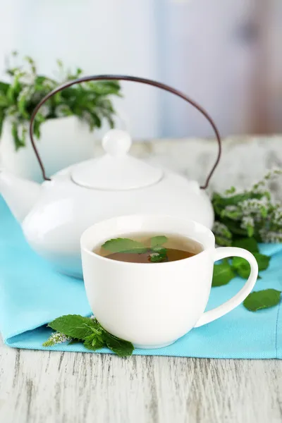 Theepot en kopje kruiden thee met verse munt bloemen op houten tafel — Stockfoto