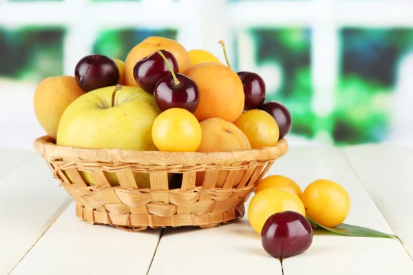Frutos de verão brilhantes na cesta na mesa da janela no fundo natural — Fotografia de Stock