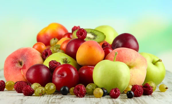 Assortment of juicy fruits, on wooden table, on bright background — Stock Photo, Image