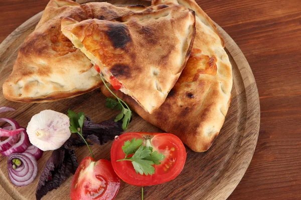 Pizza Calzone na dřevěné desce na dřevěný stůl — Stock fotografie