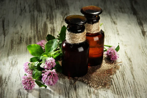 Medicin flaskor med klöver blommor på träbord — Stockfoto