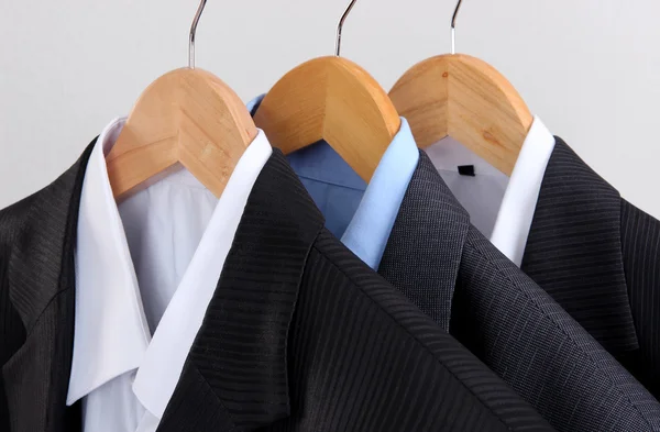 Anzüge mit Hemden auf Kleiderbügeln auf hellem Hintergrund — Stockfoto