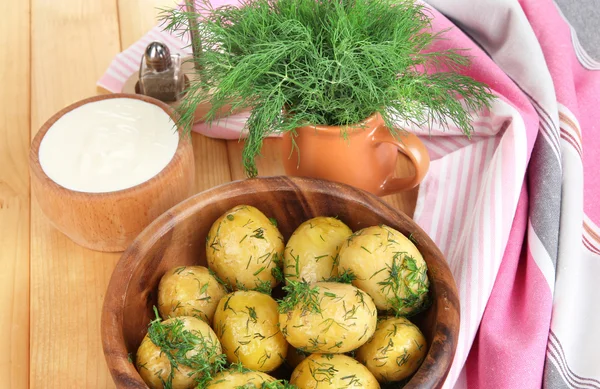 Boiled potatoes on wooden bowl near napkin on wooden table — Stock Photo, Image