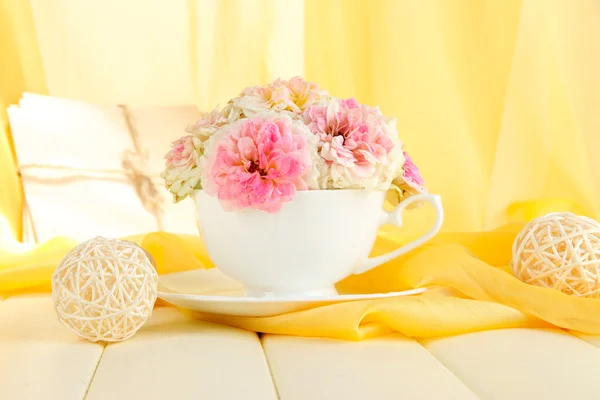 Rosas en copa sobre mesa de madera sobre fondo de tela amarilla — Foto de Stock