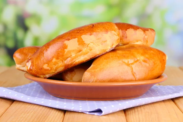 Fresh baked pasties, on wooden table, on bright background — Stock Photo, Image