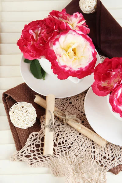 Roses in cups on napkins on wooden background — Stock Photo, Image