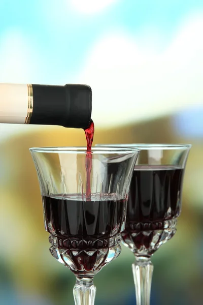 Vin rouge versé dans un verre à vin, sur fond lumineux — Photo