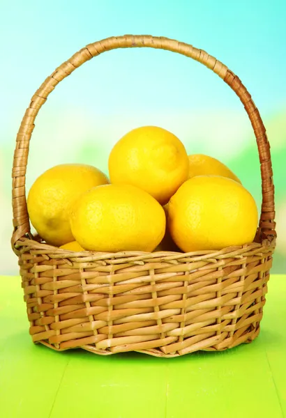 Limones maduros en canasta de mimbre sobre mesa sobre fondo brillante —  Fotos de Stock