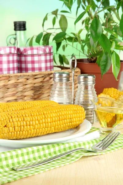 Aromatisierter gekochter Mais auf Teller auf Holztisch vor natürlichem Hintergrund — Stockfoto