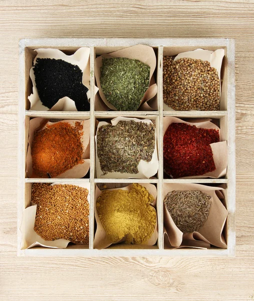 Assortment of spices in wooden box, on wooden background — Stock Photo, Image