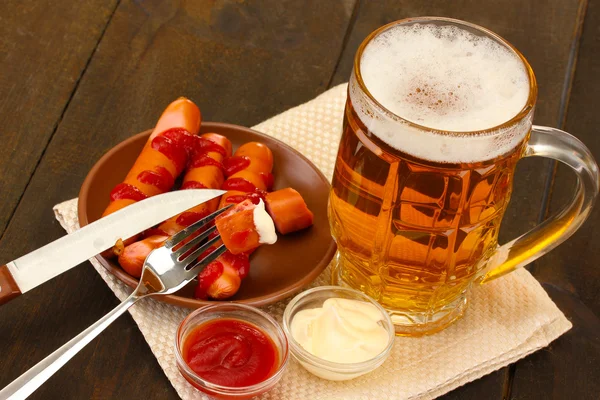 Beer and grilled sausages on wooden background Royalty Free Stock Photos