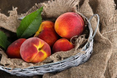 Şeftali sepeti ahşap masa üstünde çul üzerinde