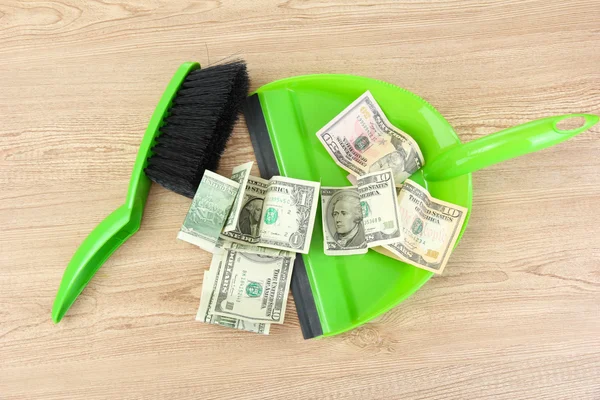 Sweeps money in the shovel on wooden background close-up — Stock Photo, Image