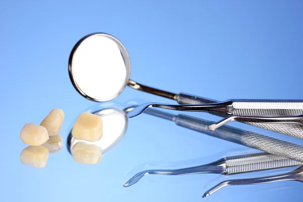 Espejo dental con dentadura postiza sobre fondo azul — Foto de Stock