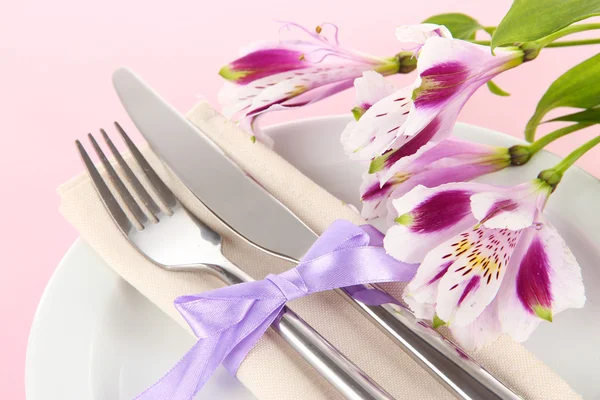 Festive dining table setting with flowers on pink background — Stock Photo, Image