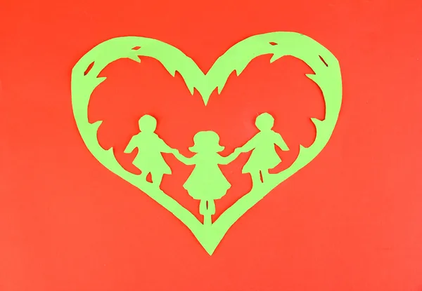 Green cut out paper heart with people inside, on color background — Stock Photo, Image