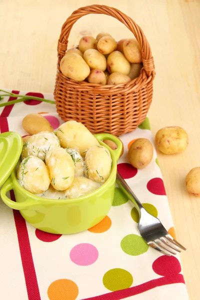 Ніжна молода картопля зі сметаною і травами на сковороді на дерев'яному столі крупним планом — стокове фото