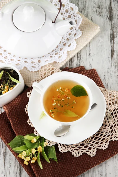 Taza de té con tilo en servilletas sobre mesa de madera — Foto de Stock